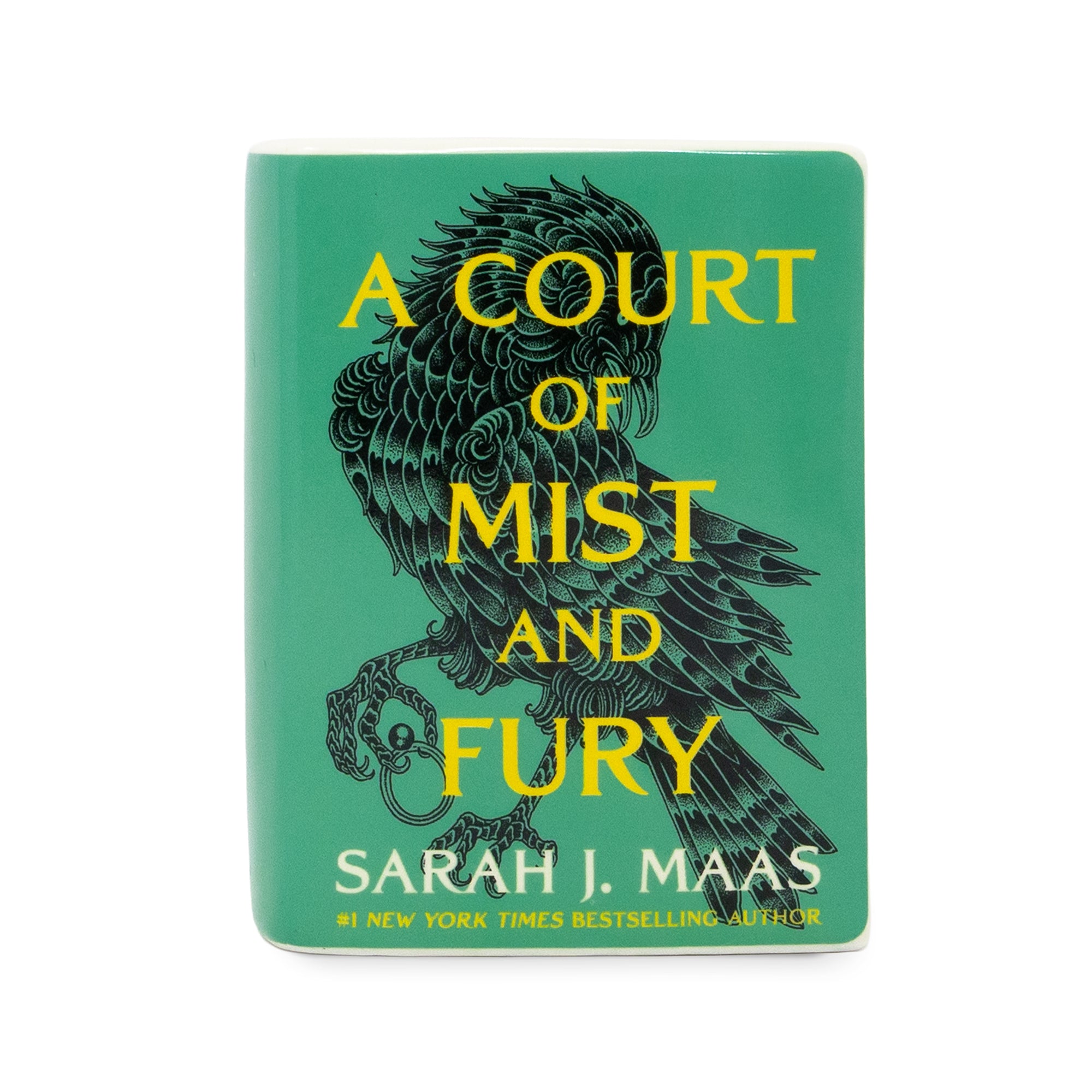 A ceramic candle featuring the book cover of 'A Court of Mist and Fury' by Sarah J. Maas, with a teal green background, a black raven illustration, and yellow text, shown on a plain white background.