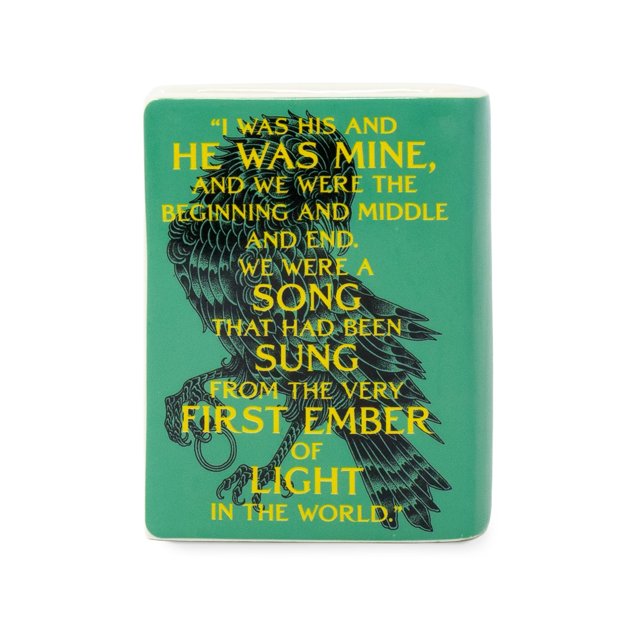 A rectangular teal ceramic candle featuring a black raven illustration