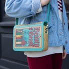 Person wearing a 'Beauty and the Beast' themed handbag with a blue and gold design.