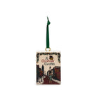 A square Christmas ornament featuring an illustrated winter street scene from 'A Christmas Carol' with a green hanging ribbon and gold loop.