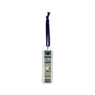 Spine of a square ceramic Christmas ornament featuring the poem 'Away in a Manger' in stylized blue, yellow, and cream illustration, hanging from a dark navy ribbon with a gold loop, on a plain white background.