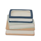A ceramic stack of three books with a small rectangular box on top, photographed on a clean white background.