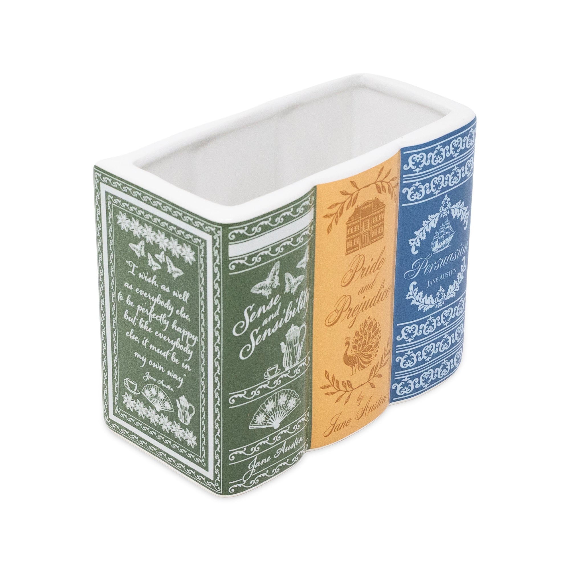 A rectangular ceramic container with a three-spine design featuring vintage book covers. The left spine is dark green with white script and botanical illustrations, the middle spine is warm orange with gold-toned text and a house illustration, and the right spine is blue with white floral patterns.