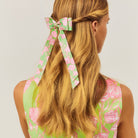 Woman with long blonde hair wearing a floral headband against a light background