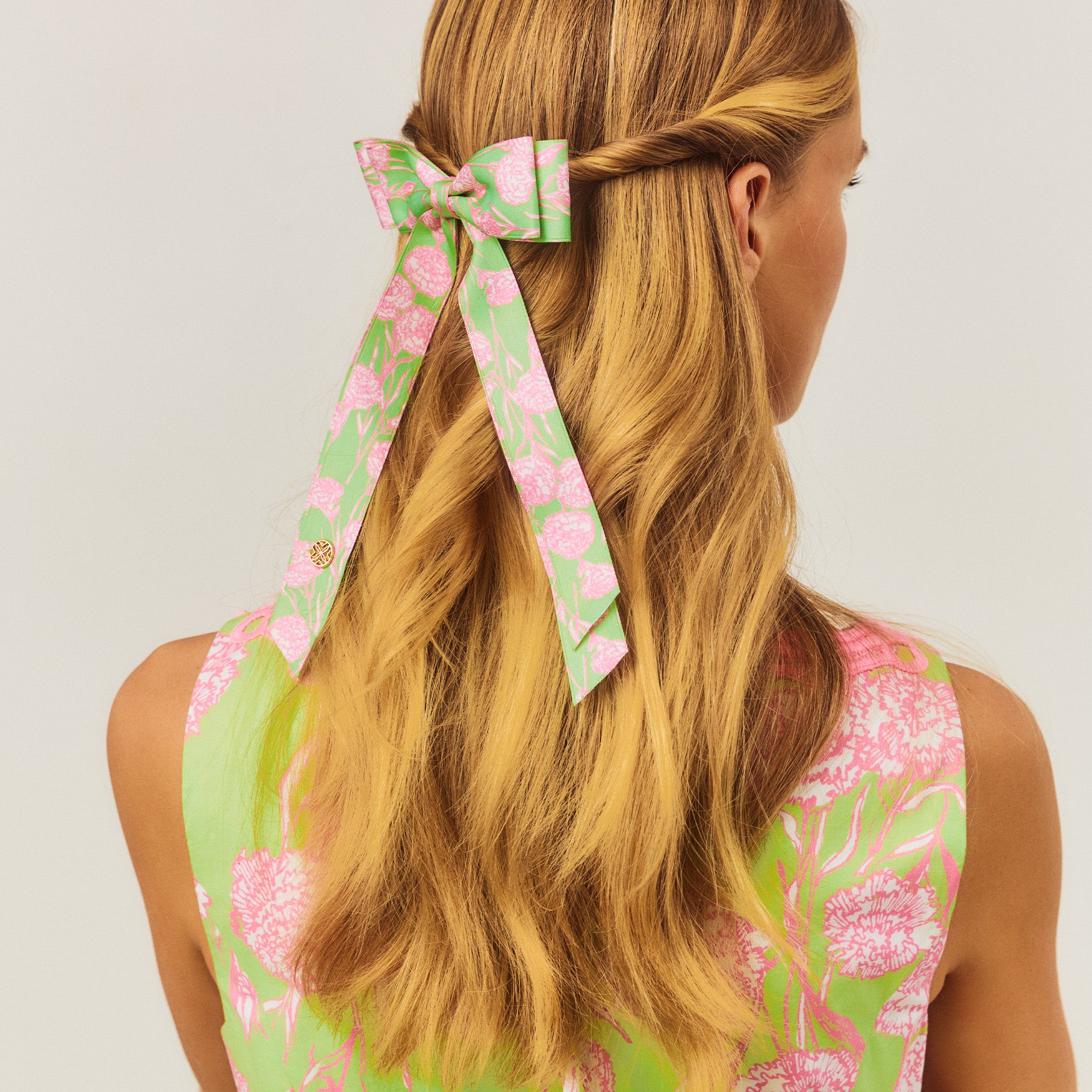 Woman with long blonde hair wearing a floral headband against a light background