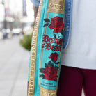 Close-up of a bag strap with 'Beauty and the Beast' design featuring roses and text.