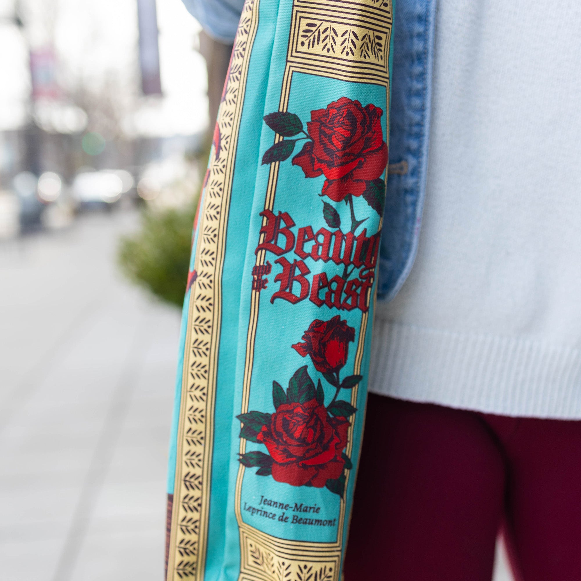 Close-up of a bag strap with 'Beauty and the Beast' design featuring roses and text.