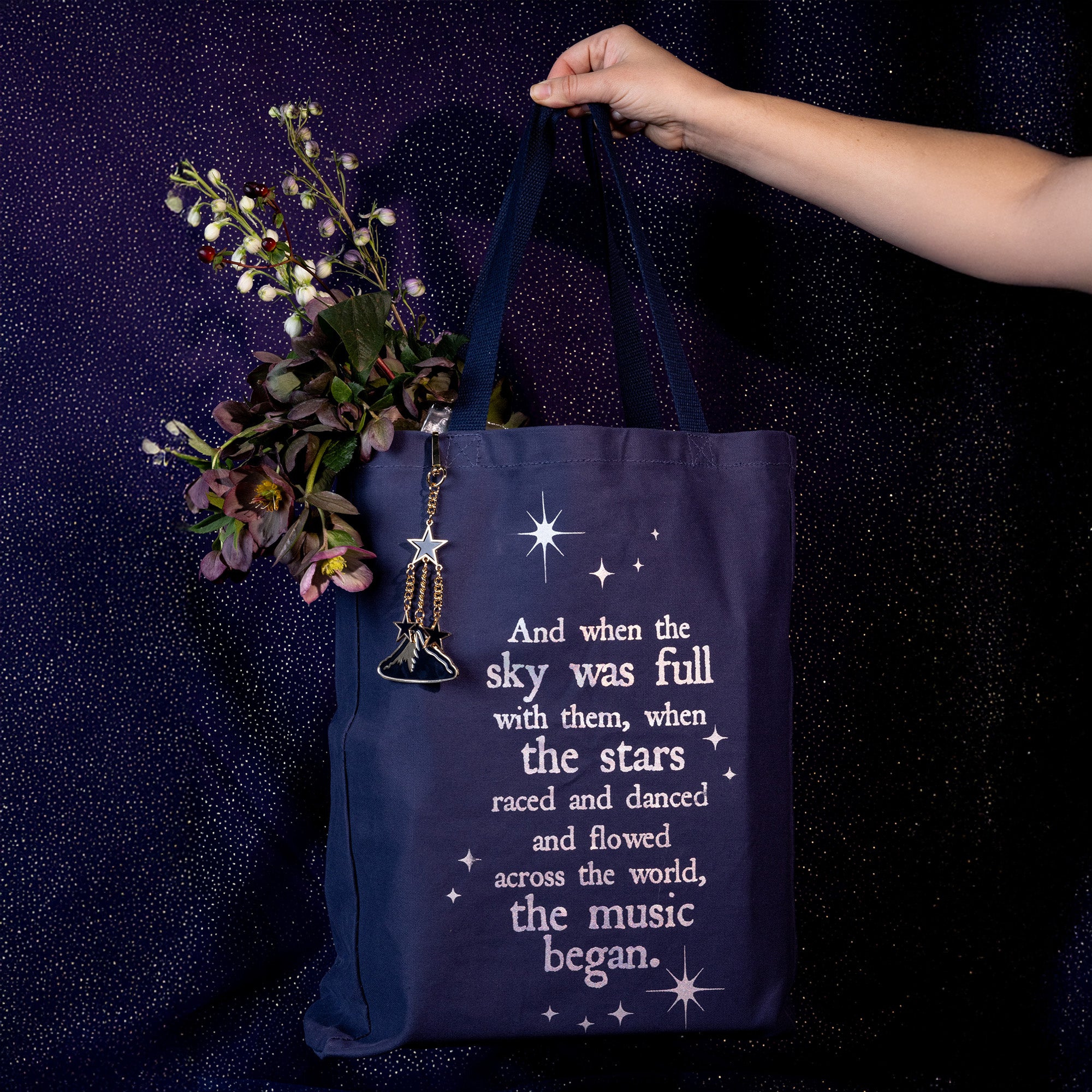 model holding navy tote bag with white text and star graphics