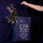 model holding navy tote bag with white text and star graphics