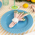 Blue plate with a decorative napkin on a striped tablecloth