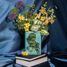 A Court of Mist and Fury' by Sarah J. Maas vase with a green cover and white spine and a bouquet inside