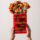 model holding book-shaped vase with 'A Court of Thorns and Roses' design