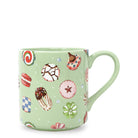 A light green ceramic mug decorated with a whimsical pattern of various colorful sweets, cookies, and candies, shown against a plain white background.