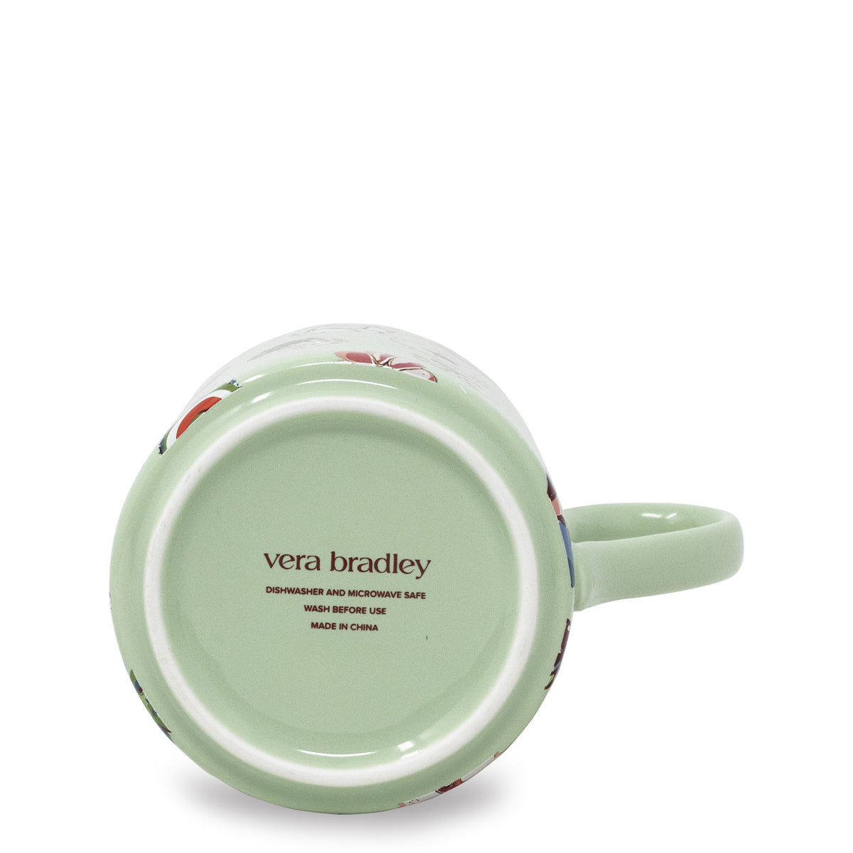 A light green ceramic mug shown from its bottom side, featuring the 'vera bradley' brand name printed in brown on the base. The mug has a pale green handle and a subtle floral pattern visible near the rim, set against a clean white background.