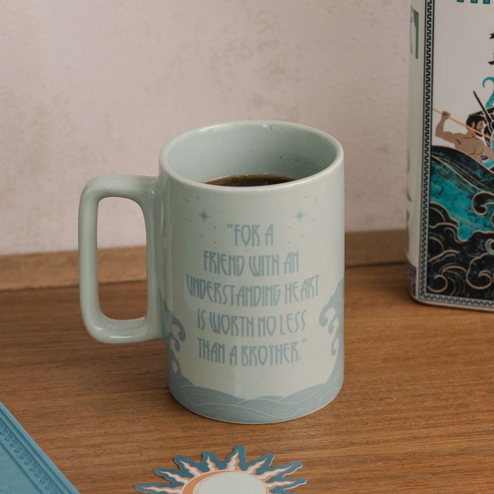 Teal mug with motivational quote on a wooden surface next to a box