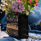 side view of Black planter with floral and fiery designs with a bouquet inside