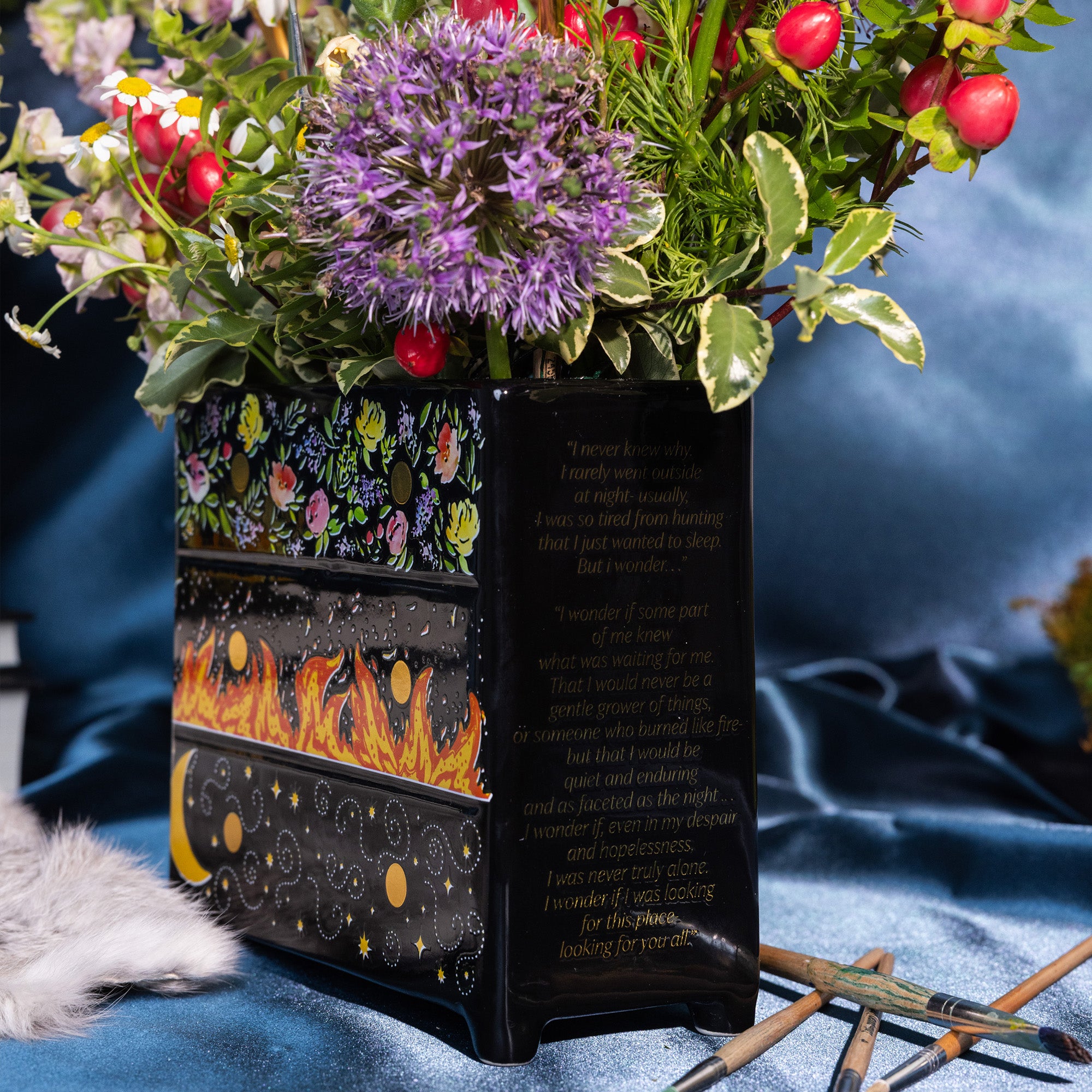 side view of Black planter with floral and fiery designs with a bouquet inside