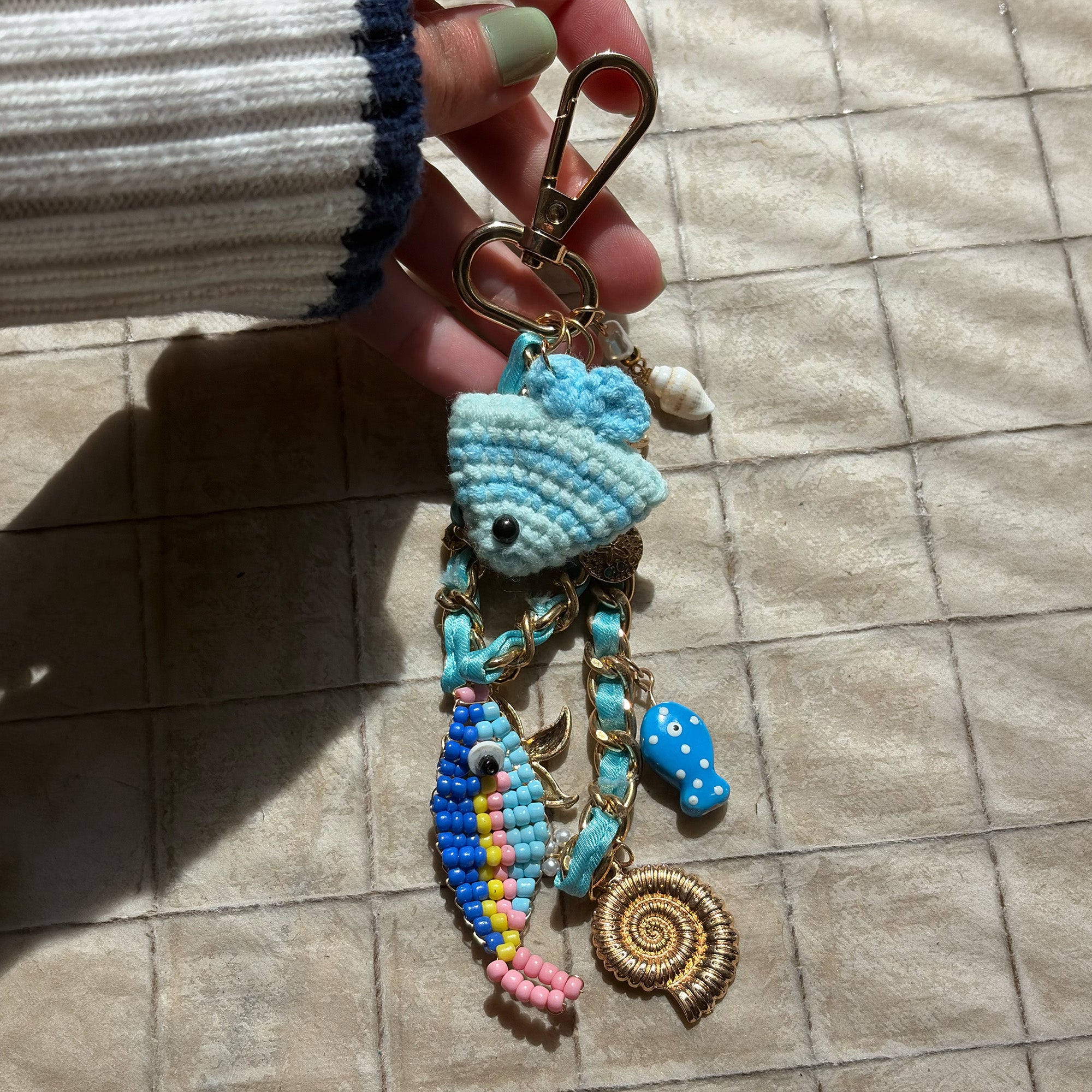 model holding decorative keychain with blue fish charm 