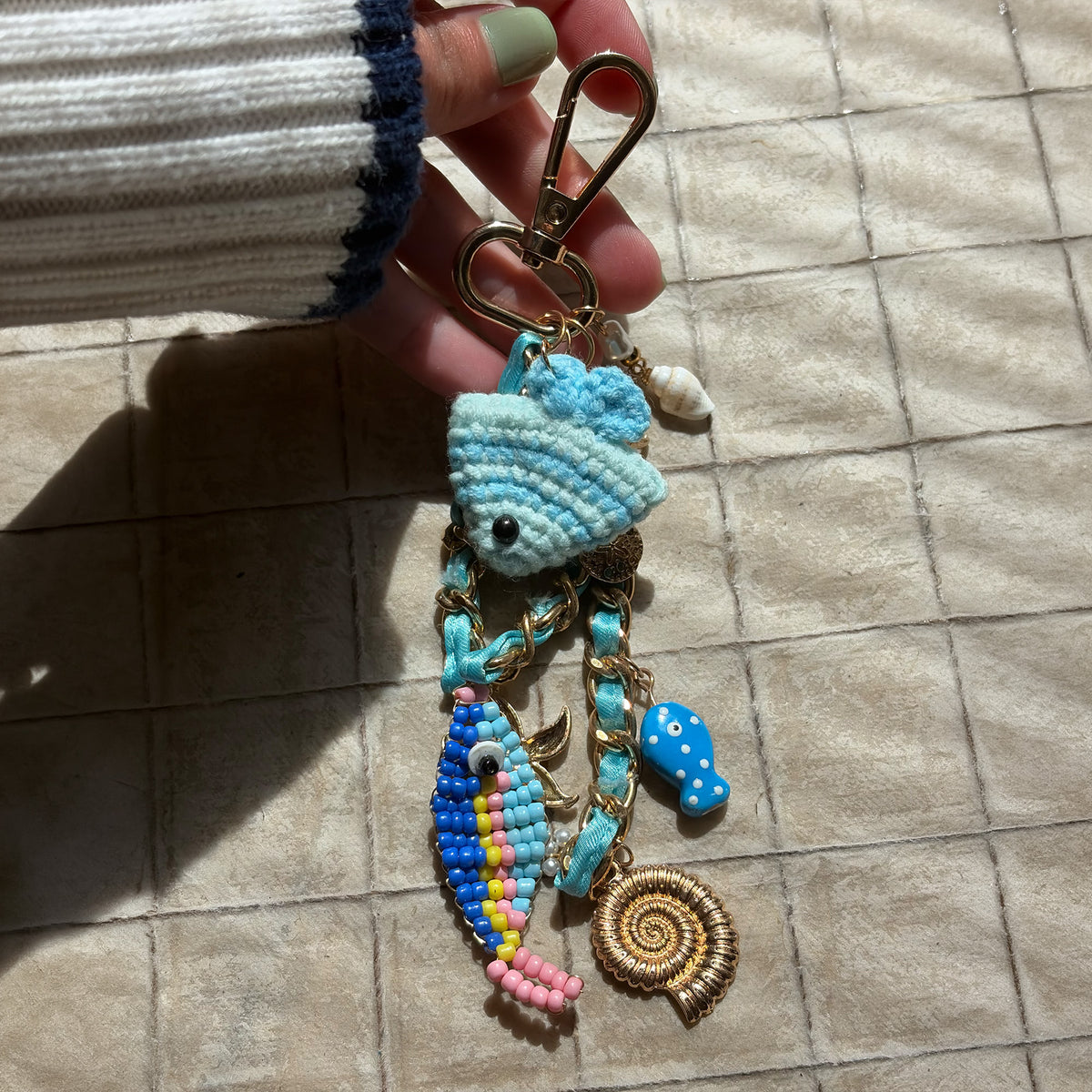 model holding decorative keychain with blue fish charm 