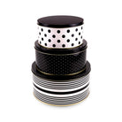 Three nested round storage tins with lids, featuring black and white patterns: the top box is white with black polka dots, the middle box is black with small white dots, and the bottom box has black horizontal stripes on a white background, all with thin gold trim.