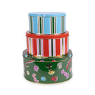 Three stacked round metal tins with colorful striped and candy-print designs on a white background.