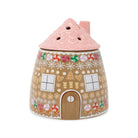 A ceramic gingerbread house-shaped vase with a pink roof, decorated with white snowflakes, colorful candy canes, and gingerbread cookie motifs on a light brown body, shown on a plain white background.