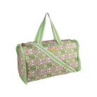 A duffle bag with a pink and green lime slice pattern, featuring green and white striped handles and a matching shoulder strap, set against a plain white background.