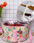Floral-patterned insulated food container with kitchen utensils on a tiled wall background