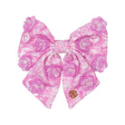 Pink floral hair bow with pearl accents on a white background