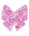Pink floral hair bow with pearl accents on a white background