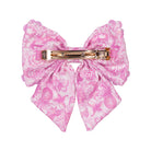 Pink floral bow with a gold clip on a white background