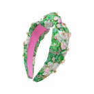 Floral headband with pink center and green leaves on a white background