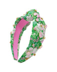 Floral headband with pink center and green leaves on a white background