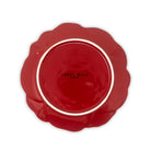 Red ceramic plate with scalloped edge on a white background