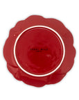 Red ceramic plate with scalloped edge on a white background