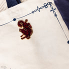 A gold-plated ACOTAR enamel lapel pin depicting a stylized red and black creature on a tote bag