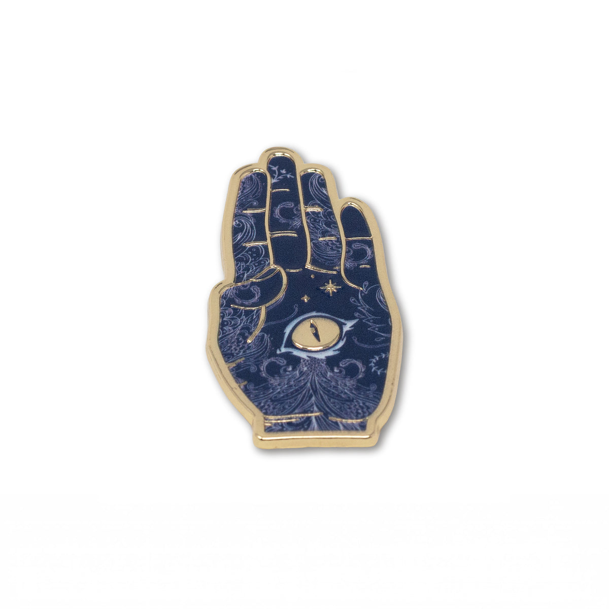 A hand enamel pin with a gold-tone metal border and a dark blue background decorated with gold celestial patterns, stars, and a central eye motif.