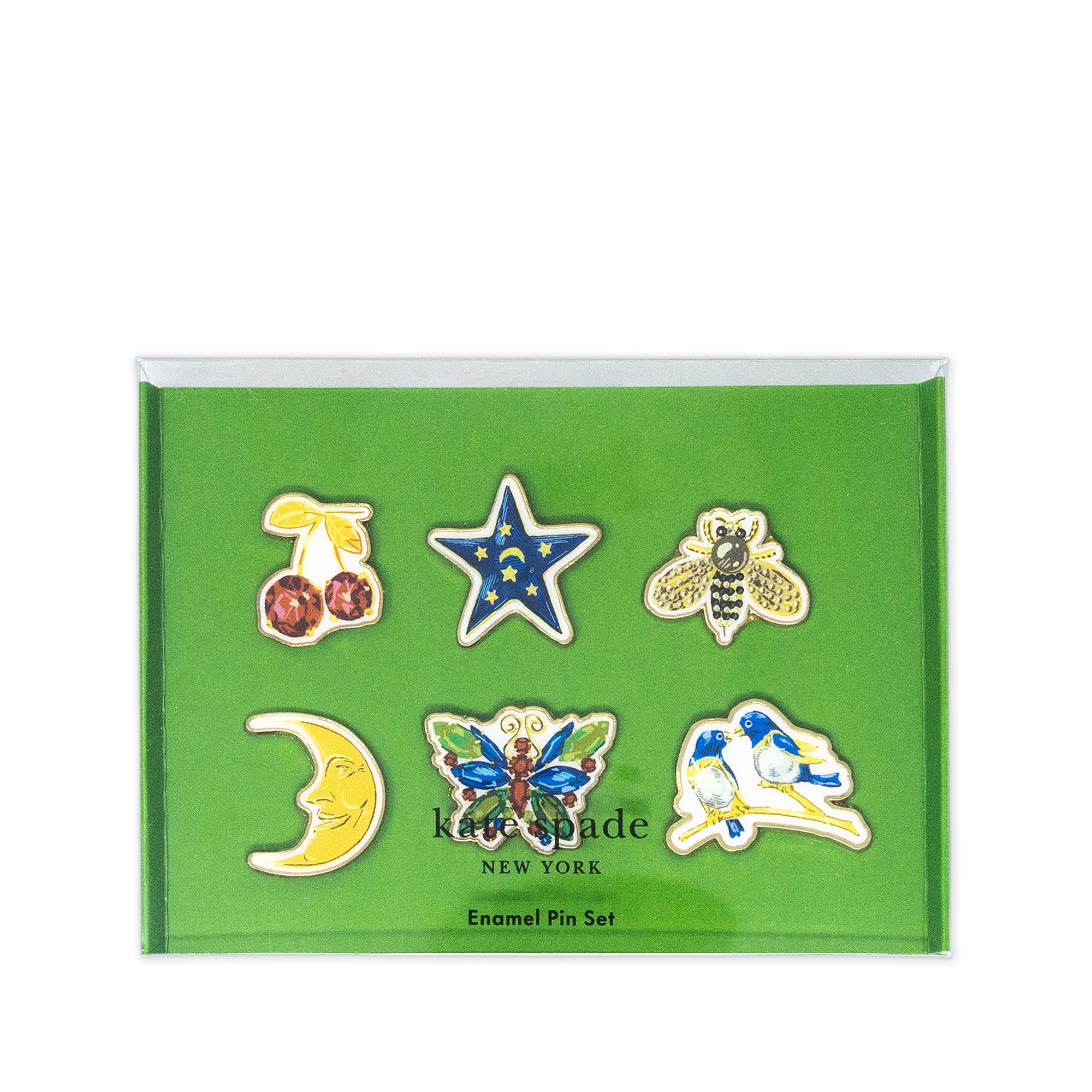 Kate Spade New York enamel pin set in a green presentation box, featuring six pins: cherries, a star, a bee, a crescent moon, a butterfly, and a bird.