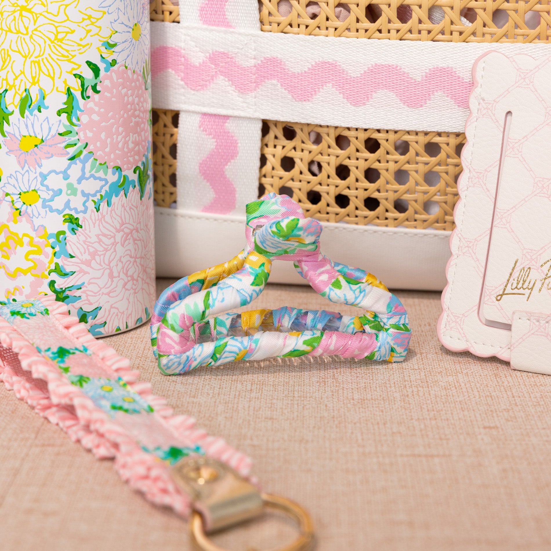 Floral-patterned strap with a gold clasp on a textured surface, with a wicker basket and floral fabric in the background.