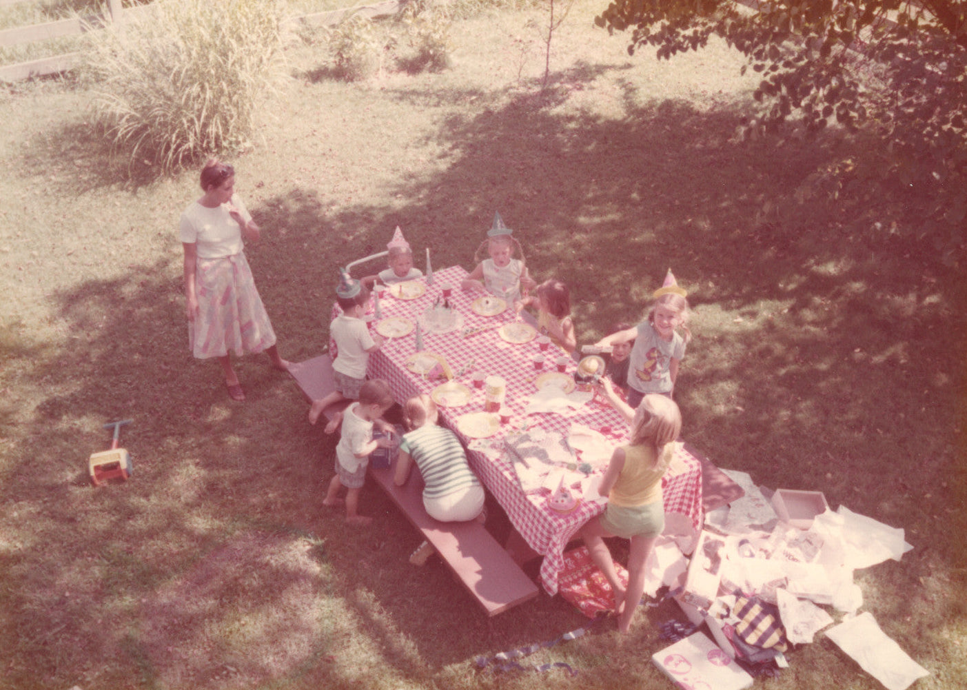 Vintage photo of a children's birthday party outdoors with a checkered tablecloth.