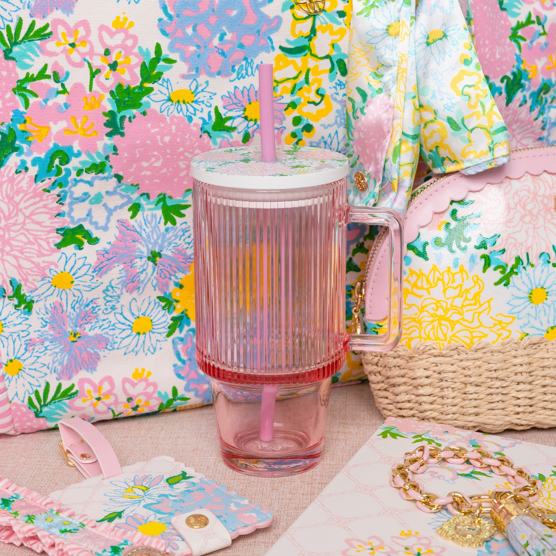 Colorful floral-patterned products including a tumbler, pouch, and bag on a matching floral background.