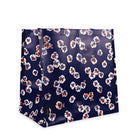 A shopping  bag with a dark navy blue background and an all-over floral pattern in white, orange, and red, shown on a plain white background.