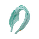 Turquoise headband with a small button on a white background