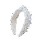 A white textured fabric headband adorned with small white faux pearls and a tiny gold clasp, shown against a plain white background.