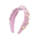 A light pink textured fabric headband with a twisted knot design, decorated with gold-tone metal settings and iridescent rhinestones, shown on a plain white background.