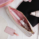 Pink hair straightener in a pink case with a matching tag on a textured surface