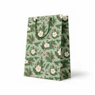 side view of green gift bag with white flowers and holly branches