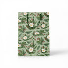 Green gift bag with white flowers and holly branches