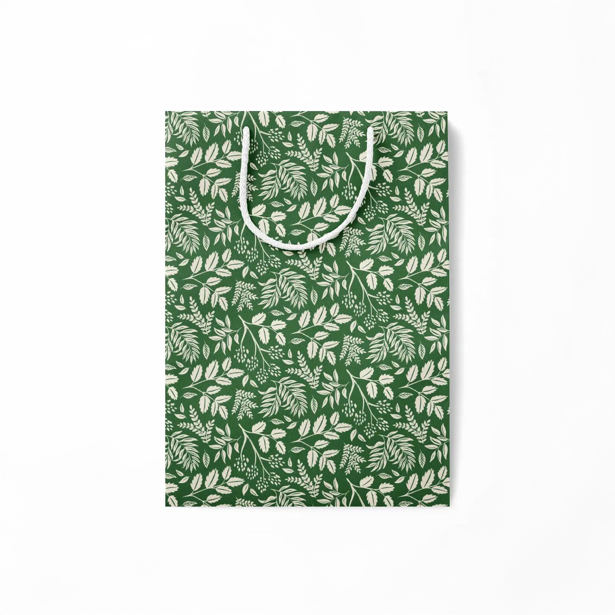 Flattened green paper gift bag with white leaf pattern on a white background