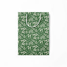 Flattened green paper gift bag with white leaf pattern on a white background